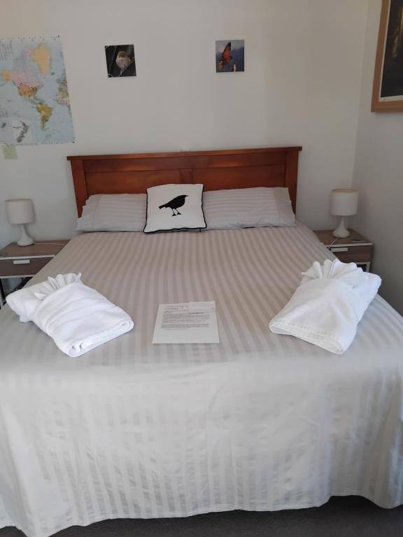 Queen bed with fresh white linen in a guest room at Al and Rosies B+B